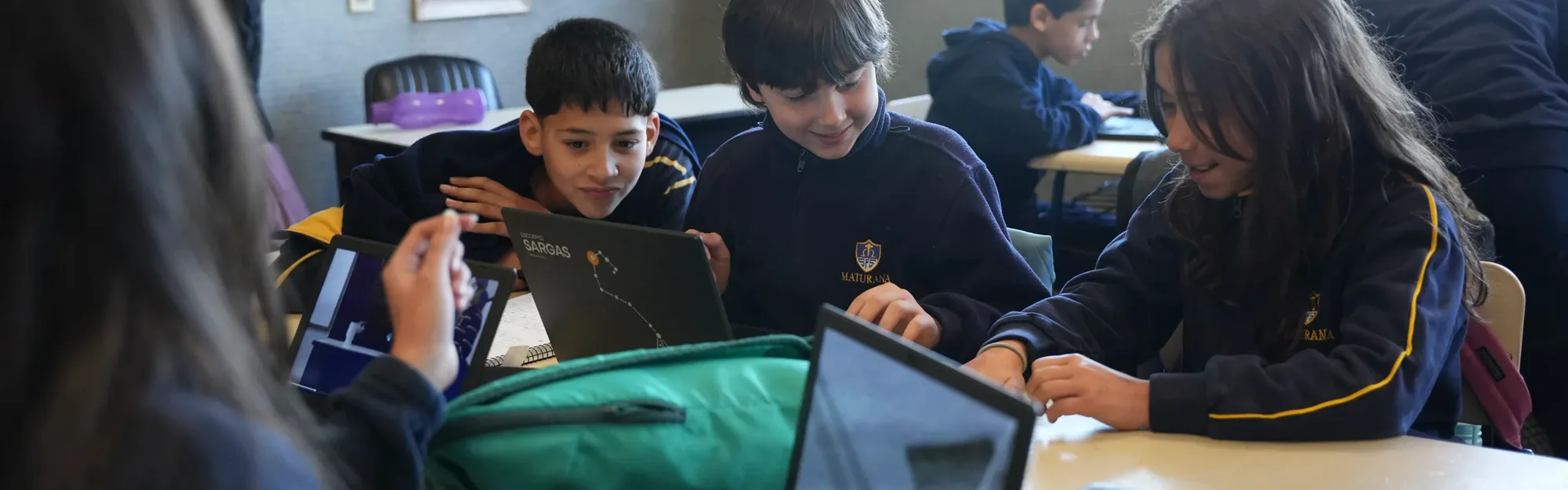 Estudiantes de Primaria trabajando en equipo con computadoras en el aula.